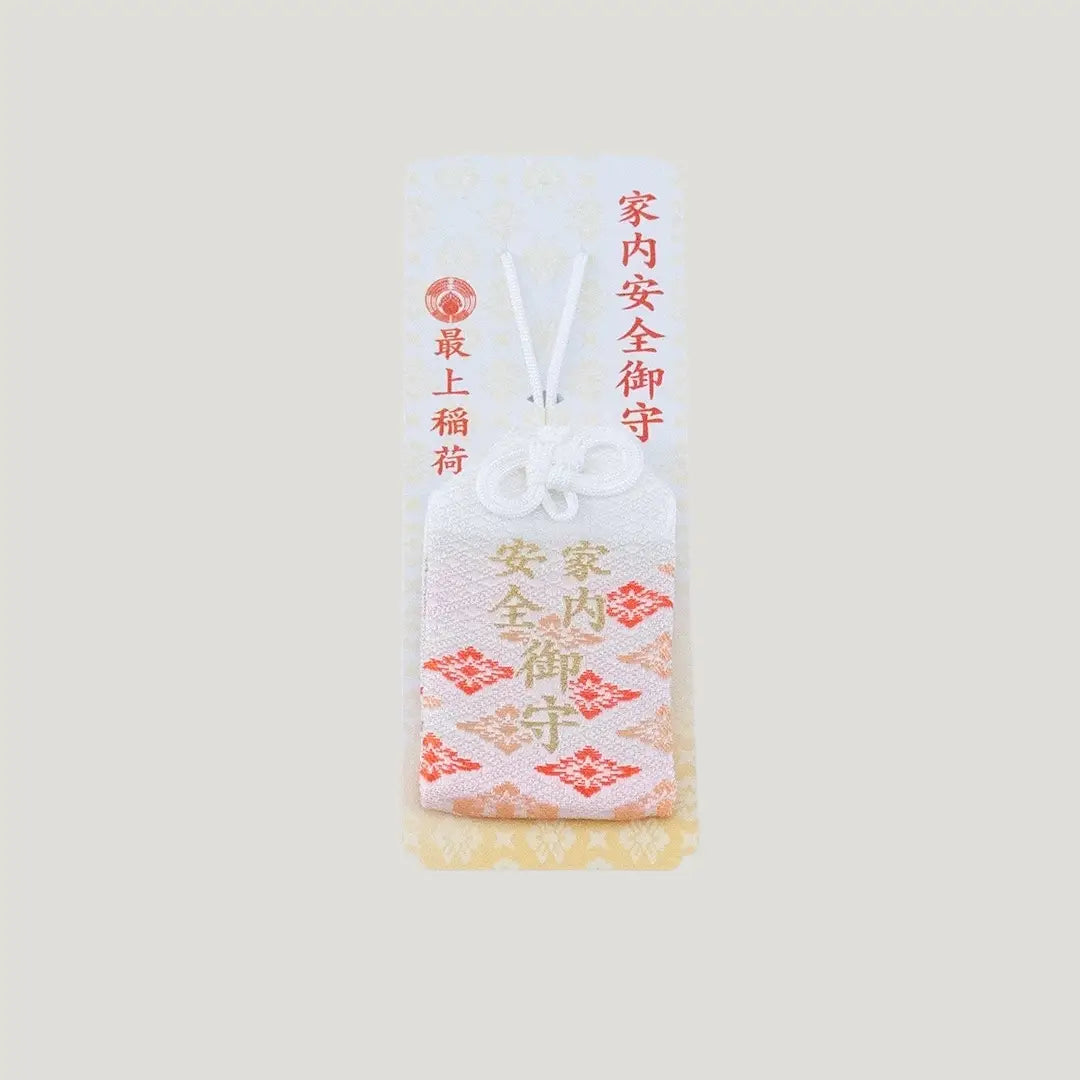 A traditional Japanese omamori for family safety from Saijo Inari temple, with white and orange/gold fabric and the kanji for 'family safety', shown on its original card.