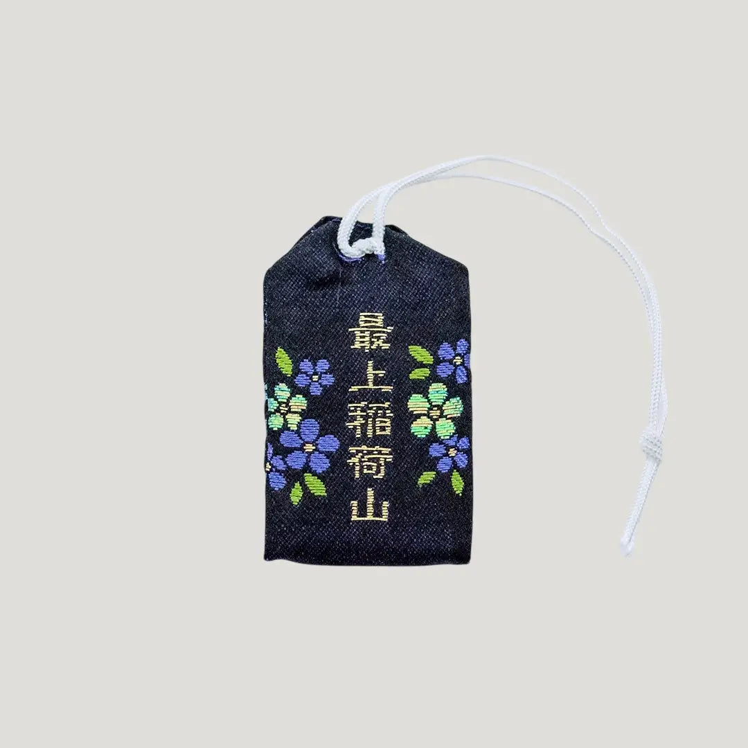 Back view of a traditional Japanese omamori for misfortune protection from Saijo Inari temple, with a black fabric and a subtle design.