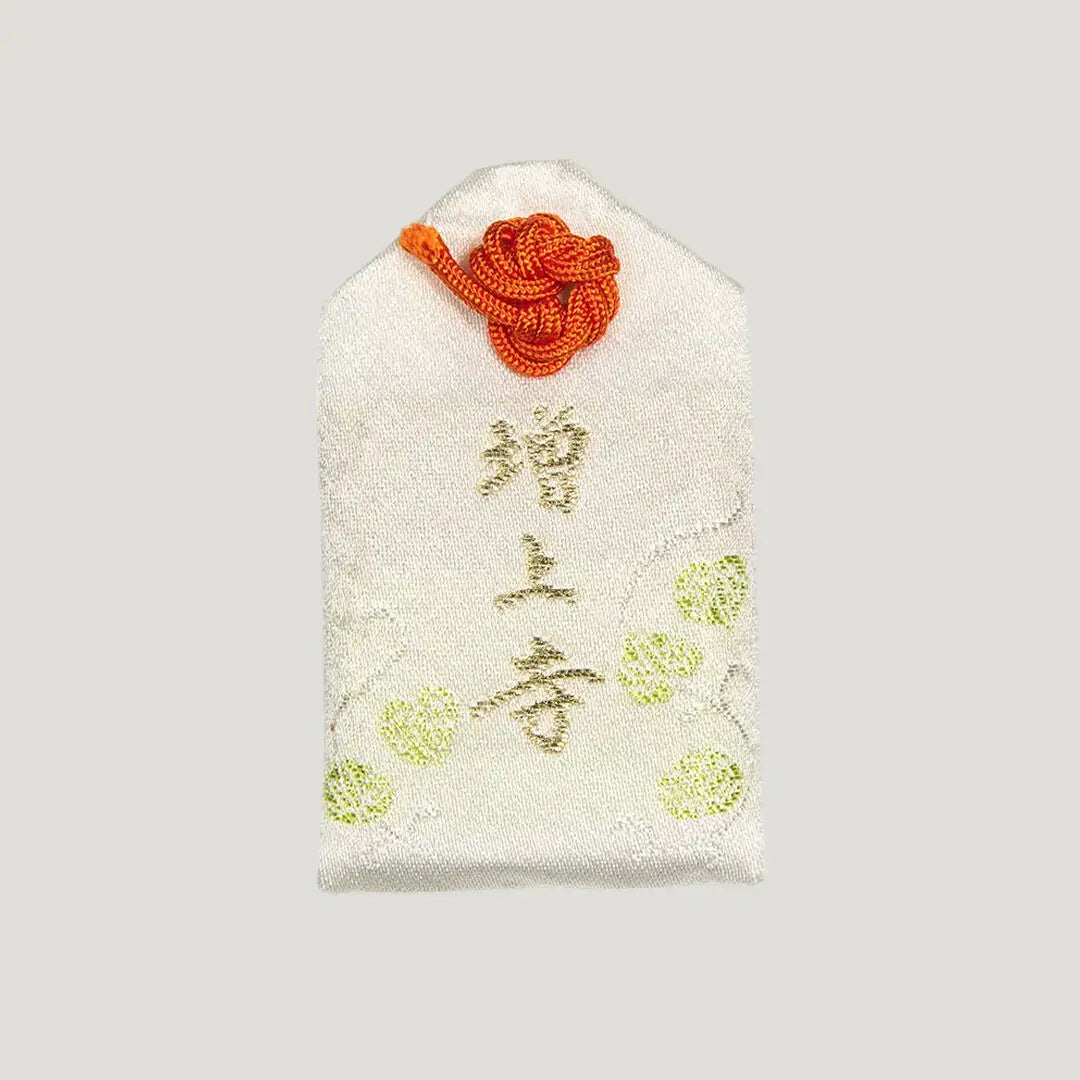 Back of 安産御守 (Safe Childbirth Omamori) from Zojoji Temple – white charm with 増上寺 in gold and green embroidery, orange cord knot