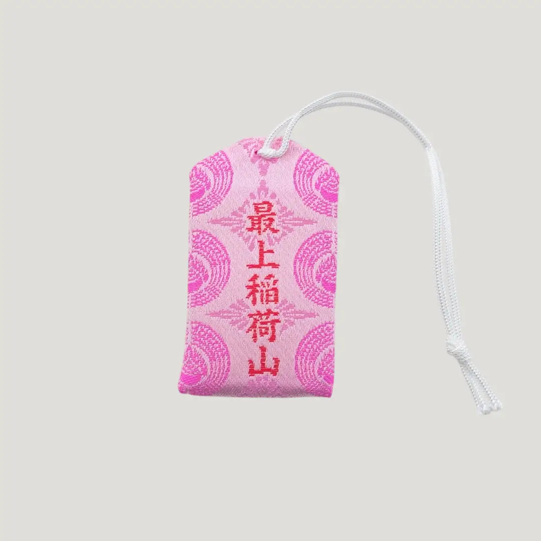 Back view of a traditional Japanese omamori for safe childbirth from Saijo Inari temple, with pink fabric and delicate gold and white embroidered designs.