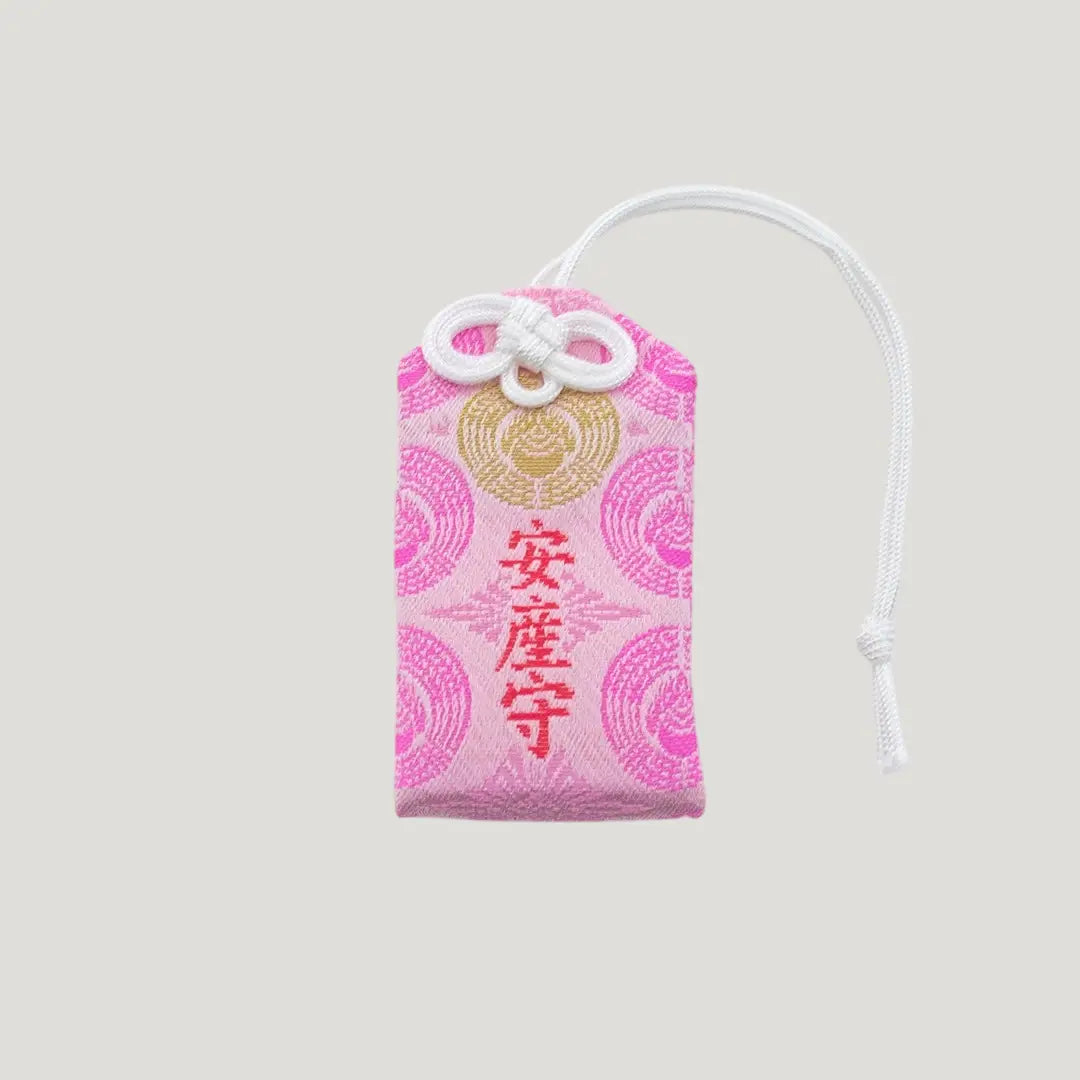Front view of a traditional Japanese omamori for safe childbirth from Saijo Inari temple, with pink fabric and delicate gold and white embroidered designs.
