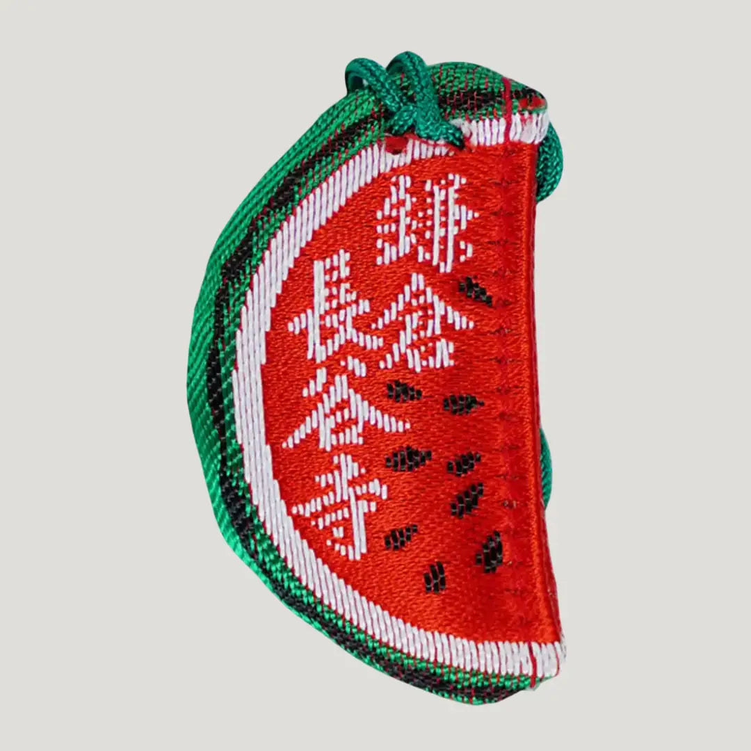 Back side of Japanese watermelon omamori charm from Hasedera Kamakura in packaging, brings good luck, health, and success in life