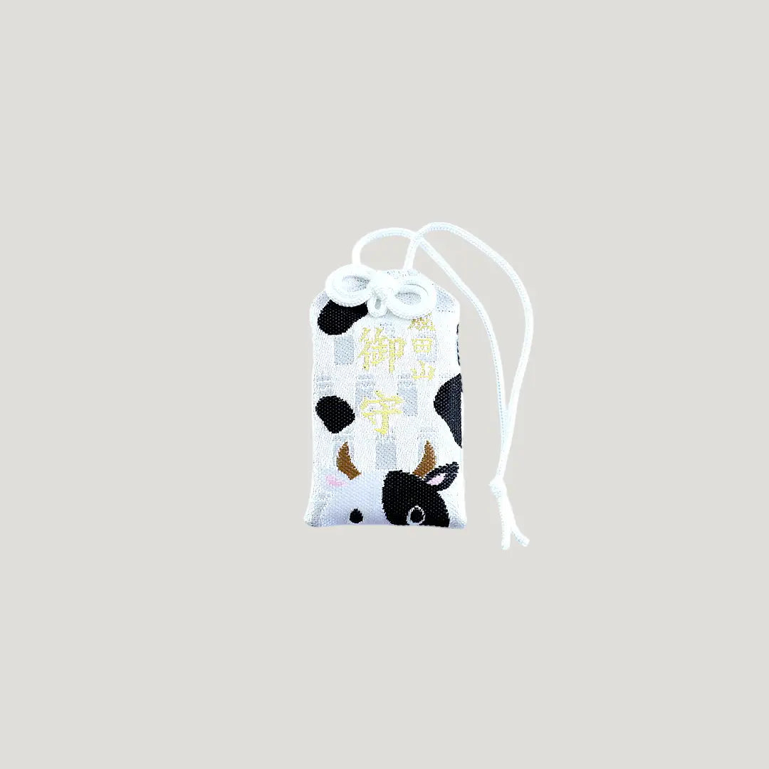 Ox Zodiac Omamori from Osaka Naritasan Fudoson featuring a black and white cow design with white cord