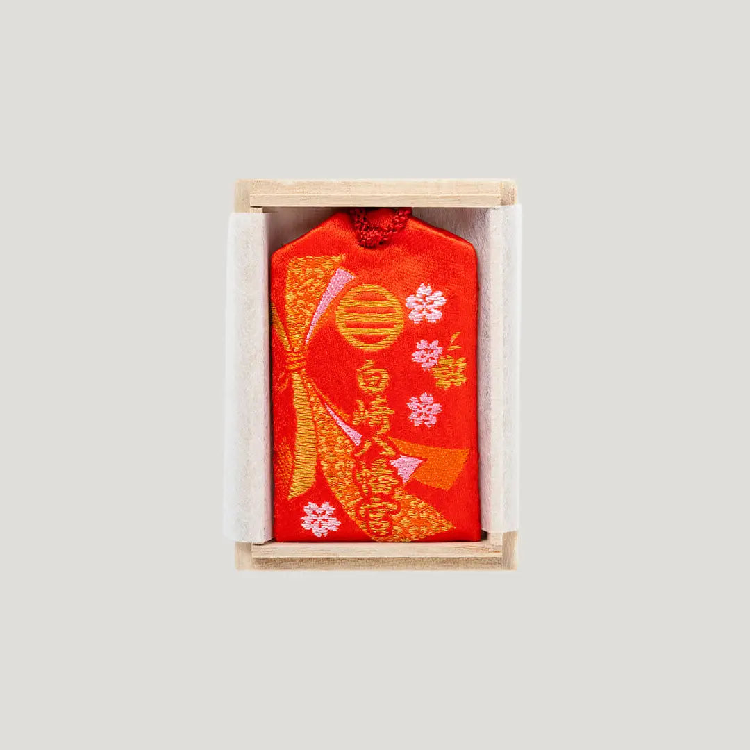 Back of Career Success Omamori with red embroidery in wooden box showing Shirasaki Shrine name