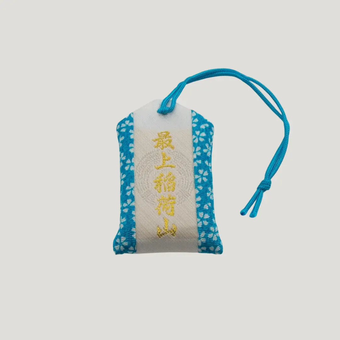 Back view of a traditional Japanese omamori for exam success from Saijo Inari temple, with blue and white fabric and a simple design.