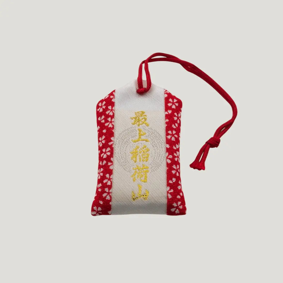 Back view of a traditional Japanese omamori for exam success from Saijo Inari temple, with red and white fabric and a simple design.