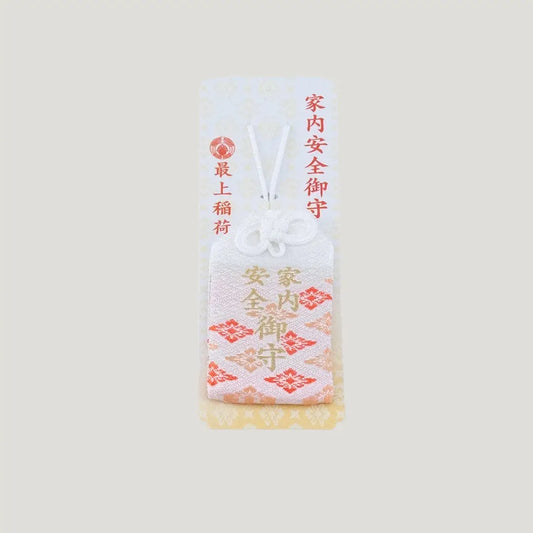 A traditional Japanese omamori for family safety from Saijo Inari temple, with white and orange/gold fabric and the kanji for 'family safety', shown on its original card.