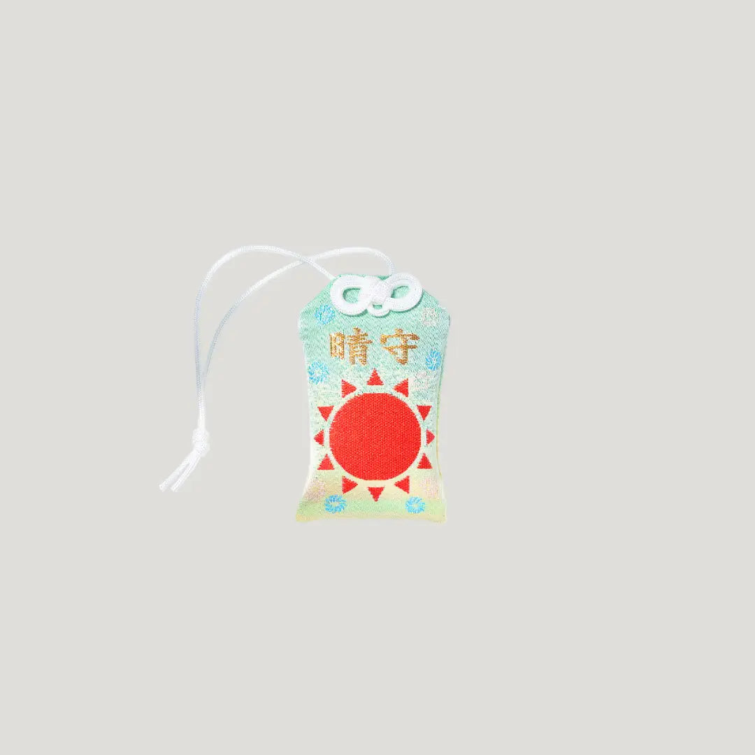 Good Weather Omamori from Kisho Shrine in Koenji featuring a bold red sun on sky-blue fabric, symbolizing clear skies and positive energy
