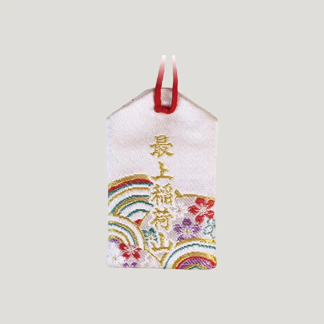 Back view of a traditional Japanese health omamori from Saijo Inari temple with white fabric and faint decorative patterns.