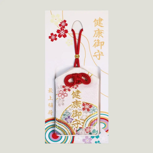 A traditional Japanese health omamori from Saijo Inari temple with a white fabric and colorful embroidered patterns.