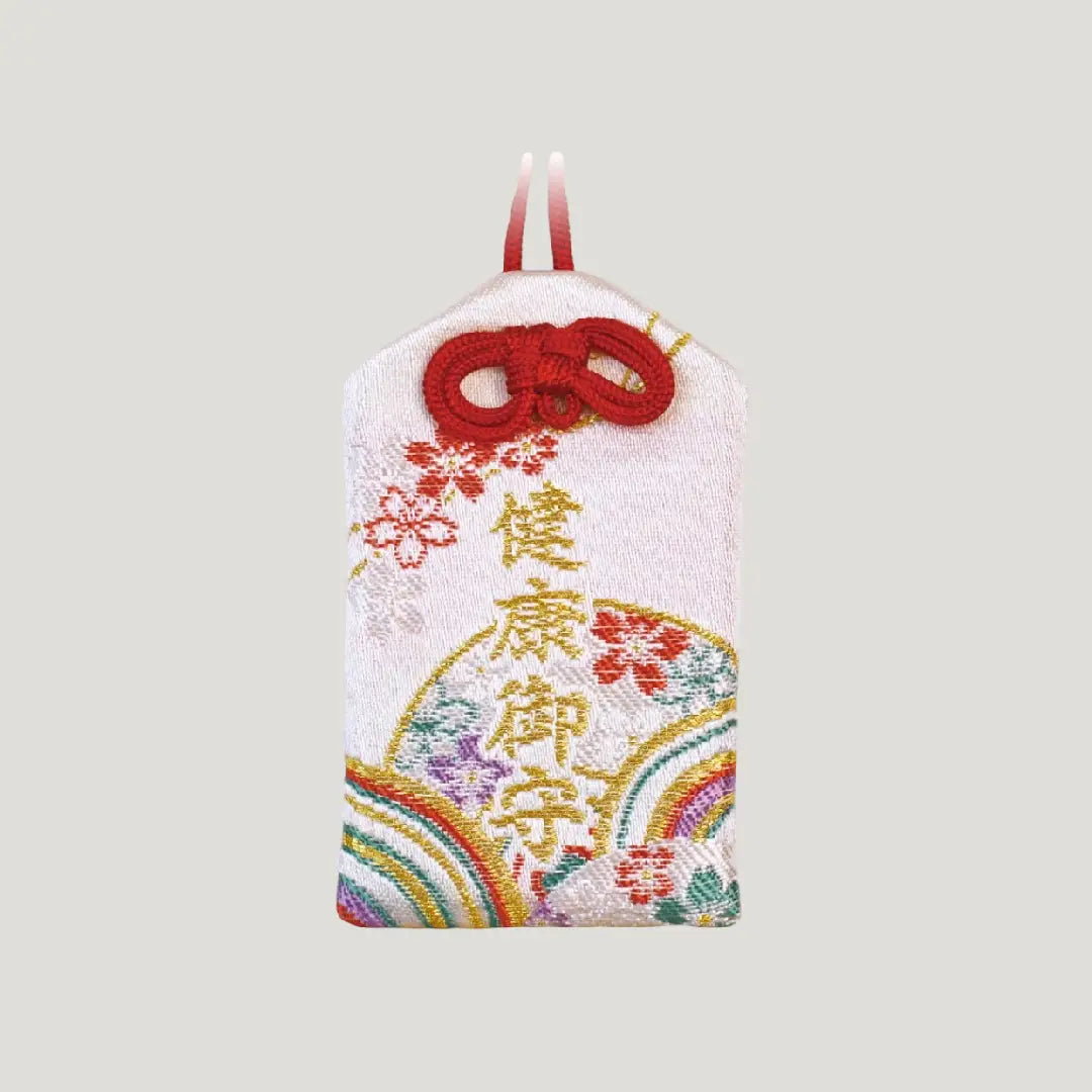 Front view of a traditional Japanese health omamori from Saijo Inari temple, showing white fabric with colorful fan and floral embroidery and red cord.