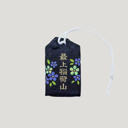 Back view of a traditional Japanese omamori for misfortune protection from Saijo Inari temple, with a black fabric and a subtle design.