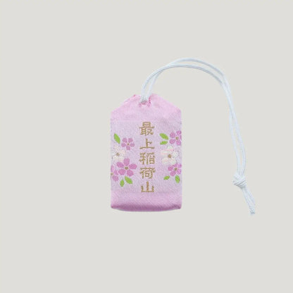 Back view of a traditional Japanese omamori for love and relationships from Saijo Inari temple, with a light peach fabric and a subtle design.