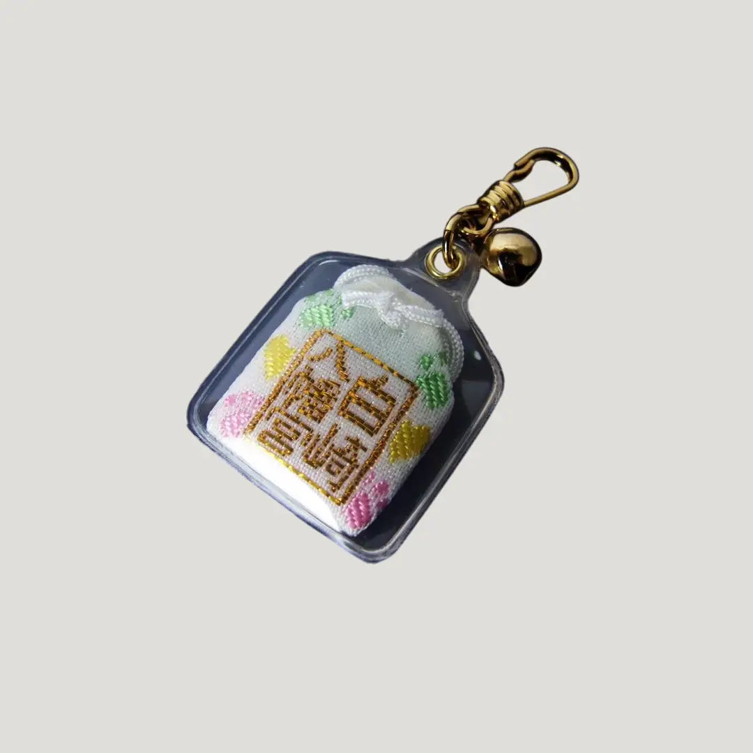 Back side of pet protection omamori (ペットお守り) from Shirasaki Shrine – embroidered white Japanese charm with pastel flowers and gold kanji for safety