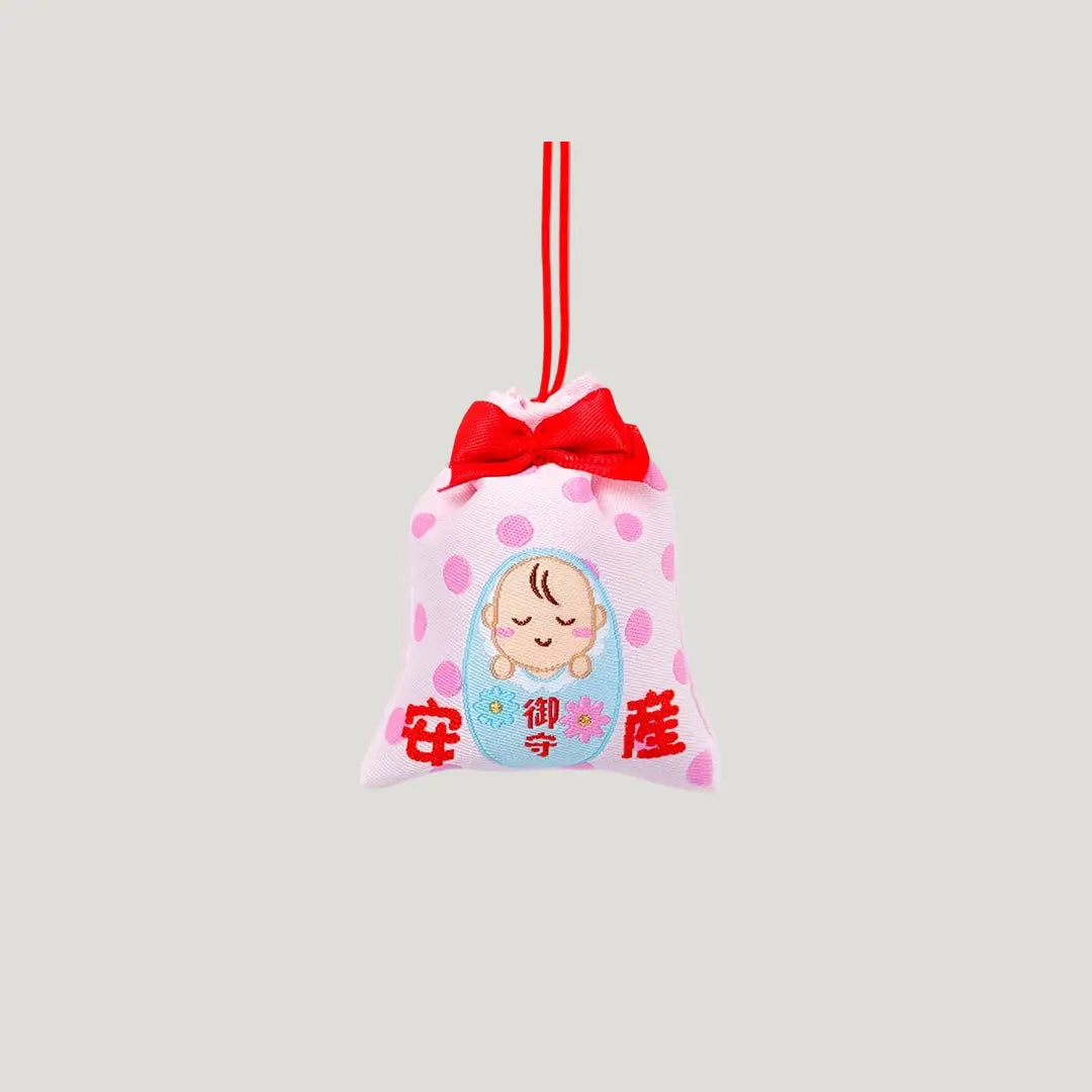 Safe Childbirth Omamori (安産お守り) front view – pink Japanese charm with baby motif, red ribbon, and polka dots from Shirasaki Shrine for pregnancy protection