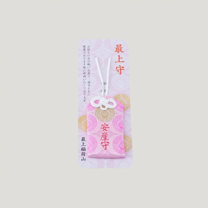 A traditional Japanese omamori for safe childbirth from Saijo Inari temple, showing a pink fabric with gold embroidery on its original display card.