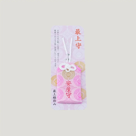 A traditional Japanese omamori for safe childbirth from Saijo Inari temple, showing a pink fabric with gold embroidery on its original display card.