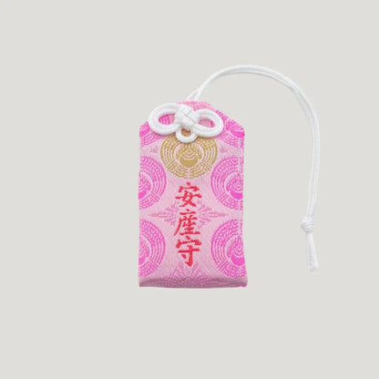 Front view of a traditional Japanese omamori for safe childbirth from Saijo Inari temple, with pink fabric and delicate gold and white embroidered designs.