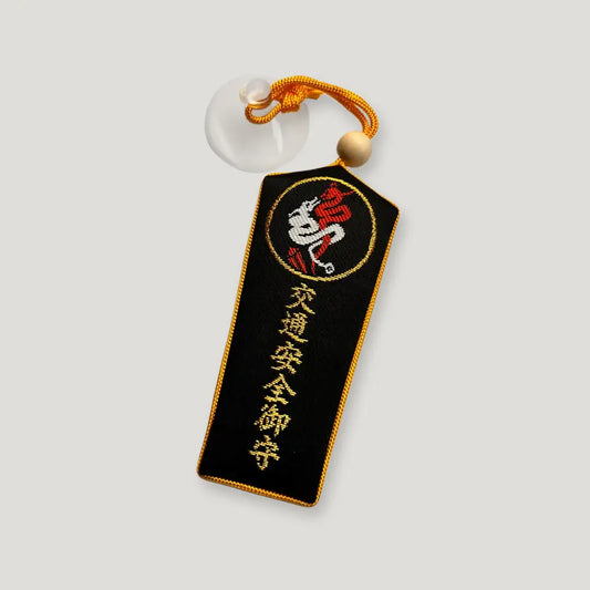 Safe Travel Omamori (交通安全守) from Izusan Shrine – black fabric charm with red and white crest, gold strap, and suction cup for car display