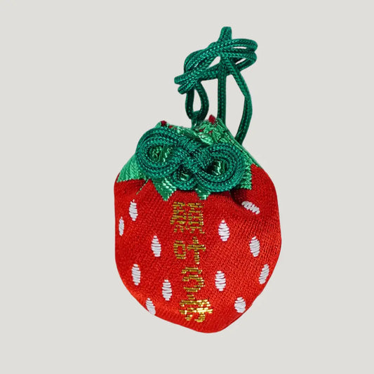 Front side of strawberry-shaped 願い叶う守 (Wish-Fulfillment Omamori) from Hasedera Temple – red charm with green cord, gold embroidered text, and white seed design