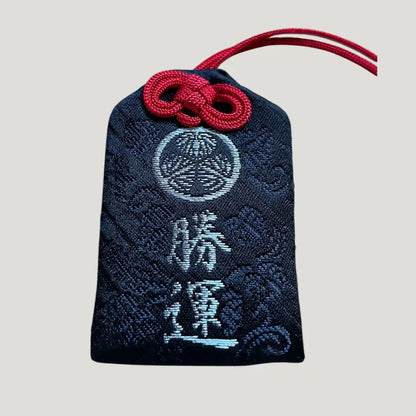 Front of 勝運御守 (Victory & Fortune Omamori) in Black (黒) from Zojoji Temple – black brocade charm with silver embroidery and red cord