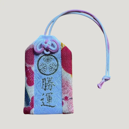 Front of 勝運御守 (Victory & Fortune Omamori) in Patterned – 雅色 from Zojoji Temple – pastel brocade fabric with floral accents and blue center strip
